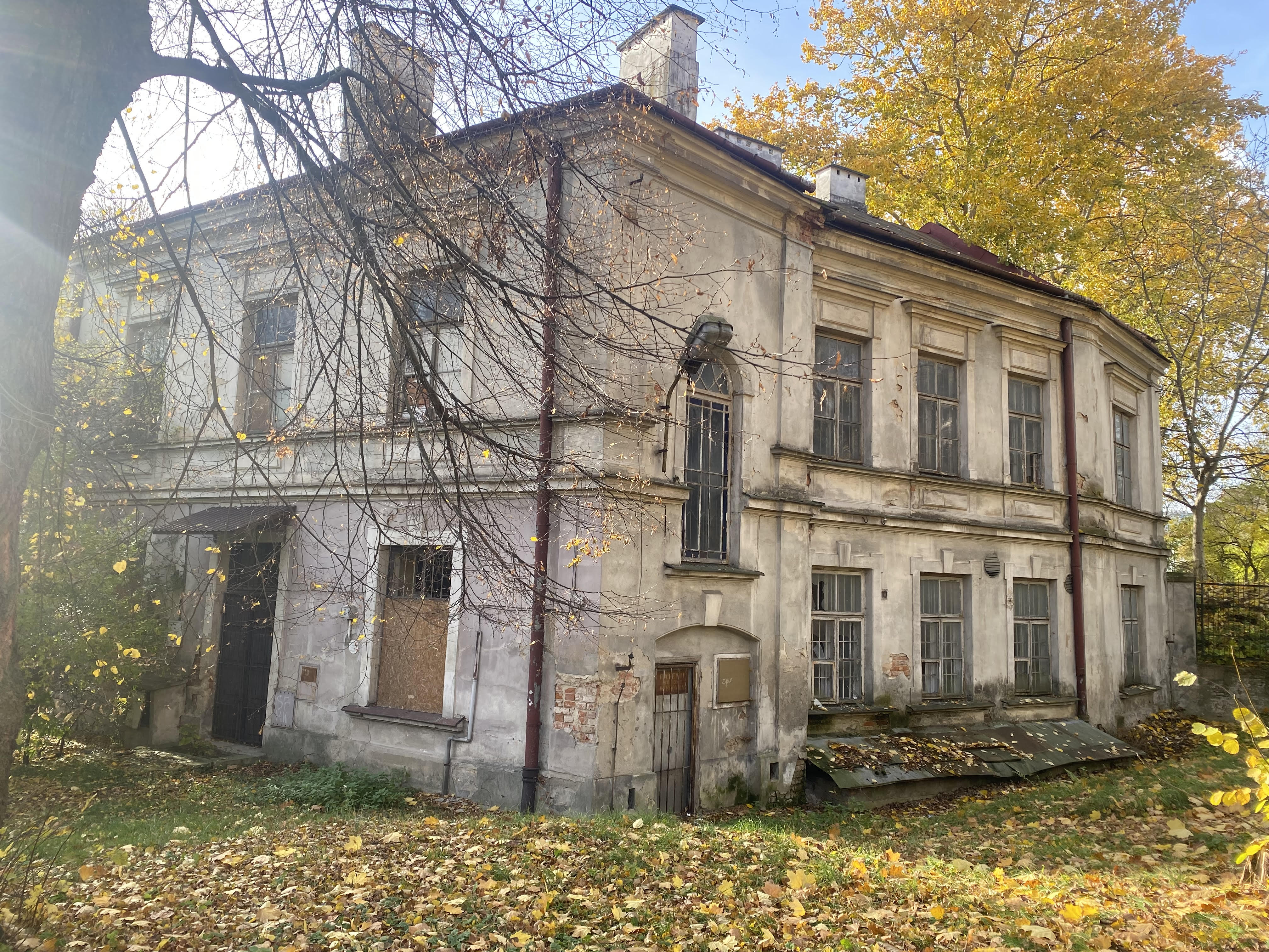 Zdjęcie w kolorze na kt&oacute;rym widać zniszczony, niezamieszkany dom i złote liście. 